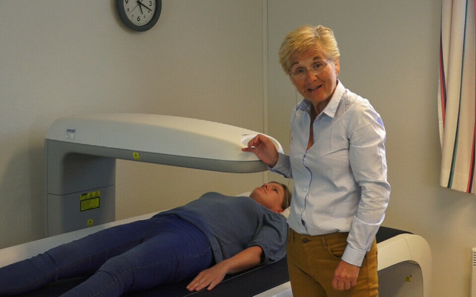 Kristin Godang demonstrerer DXA-maskinen som måler bentetthet. Den har vært sentral i mye av forskningen hun vært involvert i. Foto: Pål Wangen, Scanex Medical System AS.