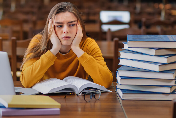 Kan man studere uten å lese pensumbøkene? Lesesal, student kjeder seg.