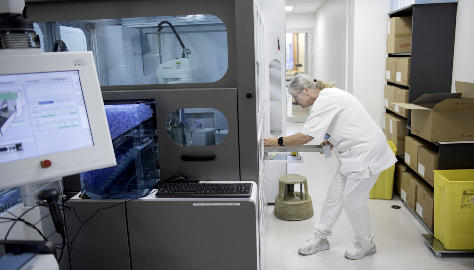 Dagens laboratorier er ikke lenger bare rom med reagensrør og mikroskoper – de er høyteknologiske miljøer med automasjonslinjer, avanserte IT-systemer og stadig økende krav til datasikkerhet, skriver kronikkforfatterne. Bioingeniør og analysemaskin
