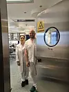 To personer i hvitt laboratorietøy står foran en dør med smittefare-symbol og teksten P3 Lab.
