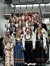 Stor gruppe personer står tett samlet i trappene i et innendørs amfi, mange i tradisjonelle klær.