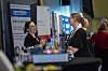 To personer i samtale ved en Gentian-utstillingsstand på en messe.
