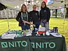 Tre personer ved en NITO-stand med brosjyrer og produkter på et grønt uteområde.